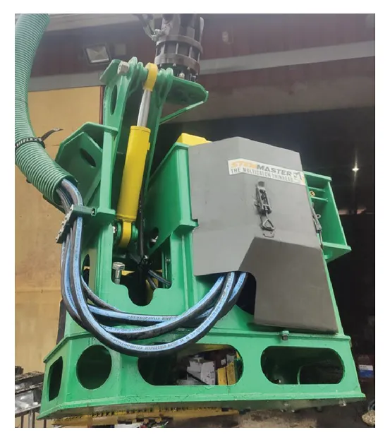 Close-up of the StemMaster green-and-yellow continuously-collecting felling head with vertical disc blade and black collector barrels
